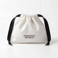 White drawstring fabric bottle bag with black ribbons and printed text on front