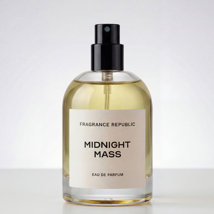 Clear glass perfume bottle labeled 'Midnight Mass Eau de Parfum' with black spray cap